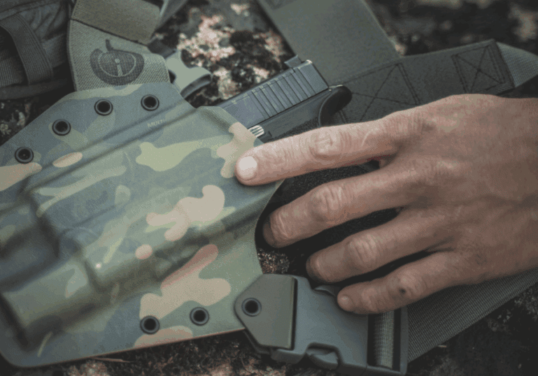 A man pulling his gun out of his GunfightersINC holster.