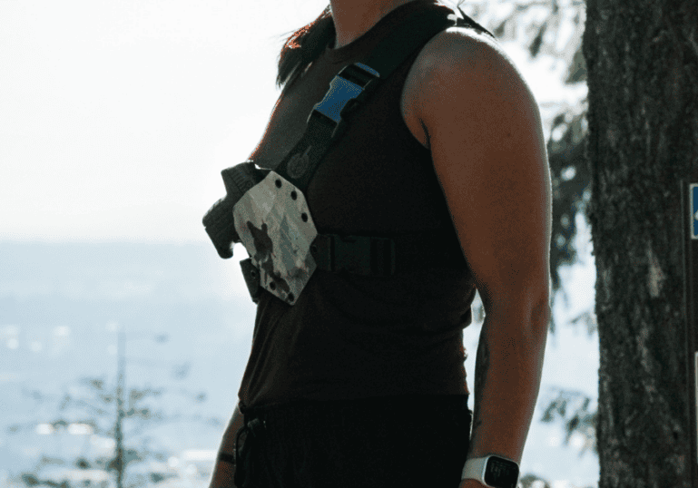 A woman wearing a GunfightersINC Kenai Chest Holster while trail running.