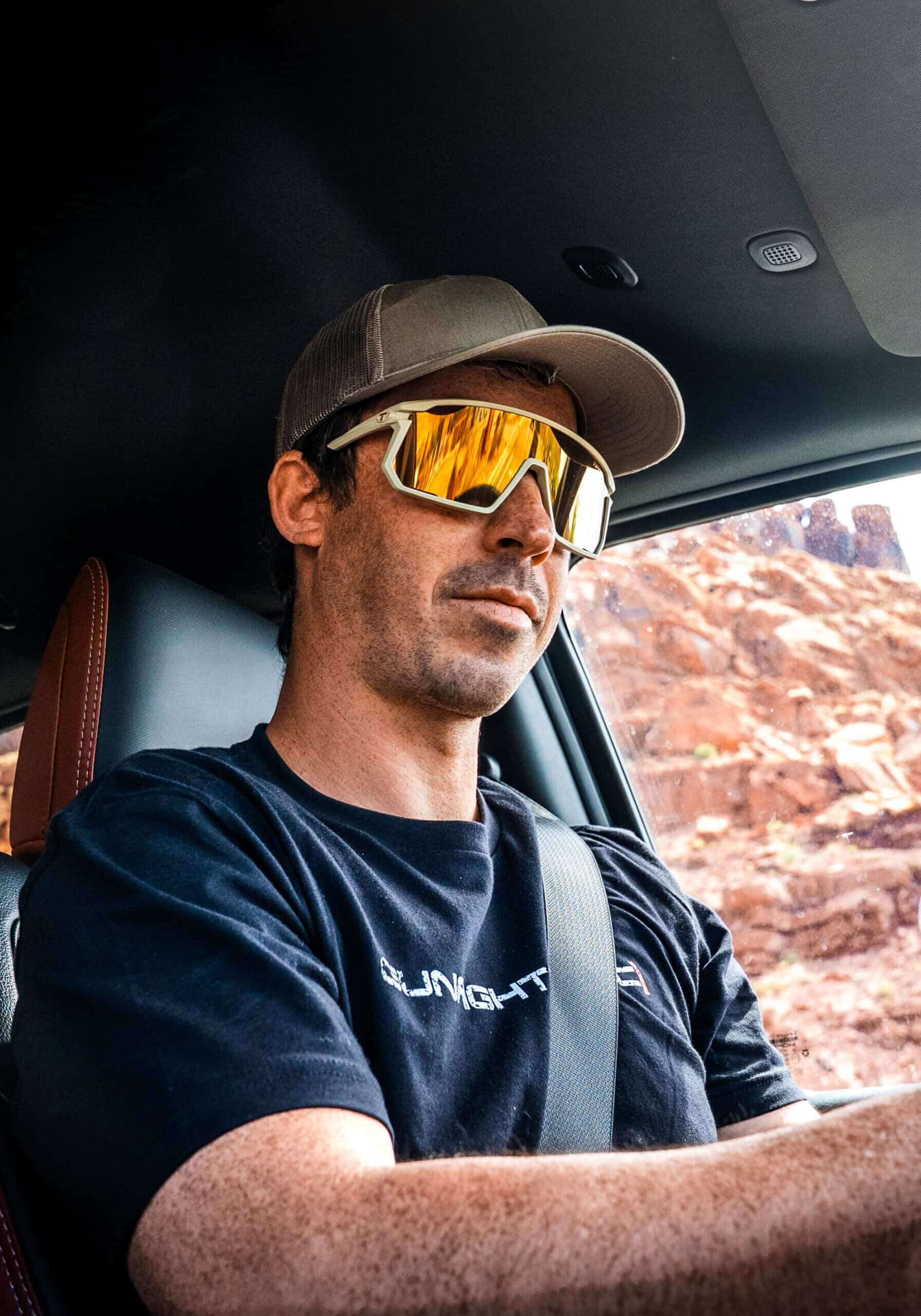 man with sunglasses driving with GunfightersINC shirt